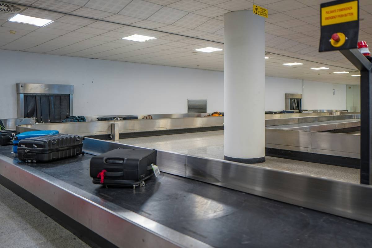 Traveler checking luggage status while holding receipt for baggage delay payout